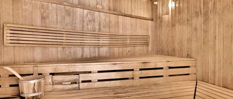 A wooden sauna with benches and a bucket.