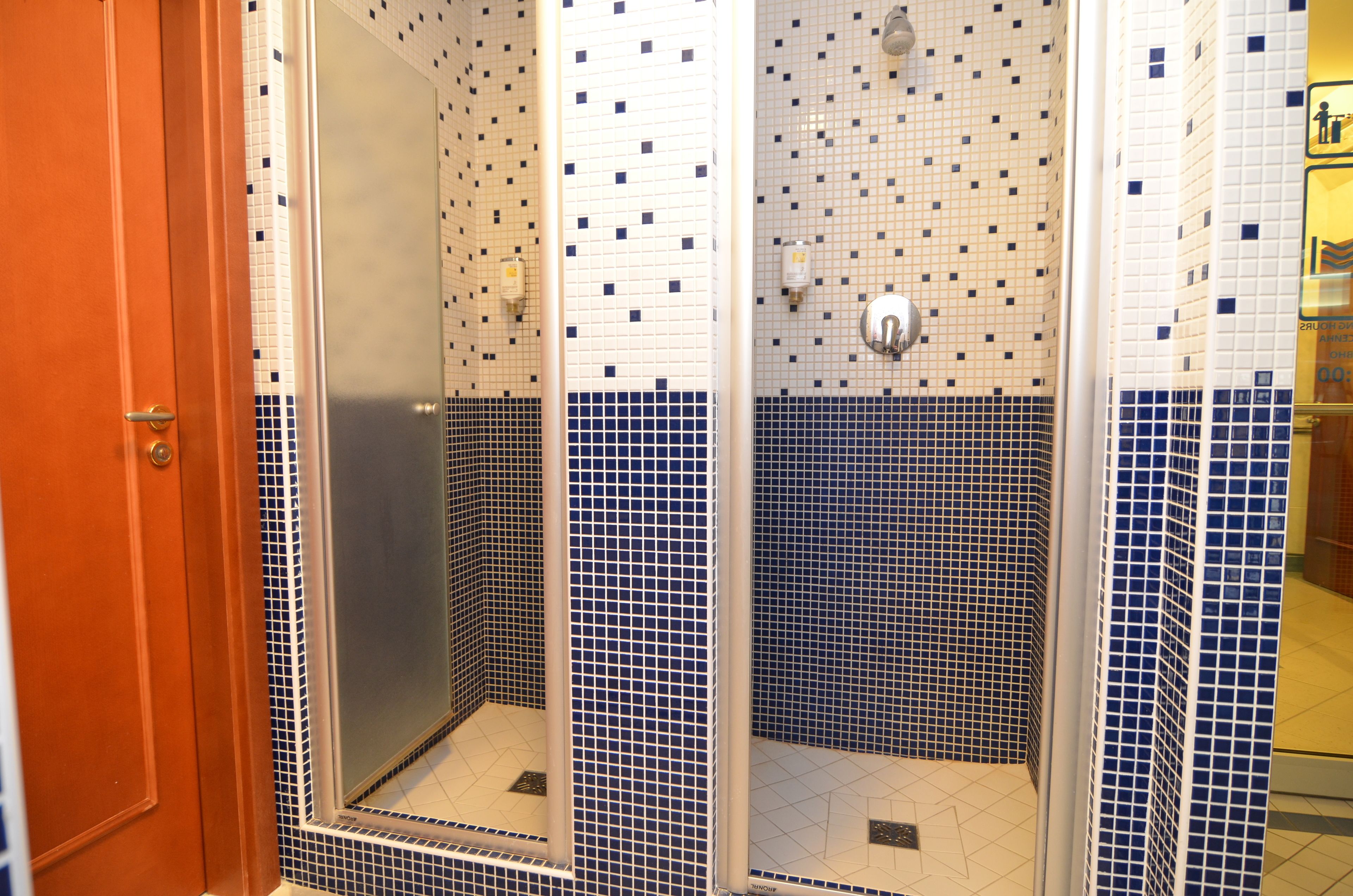 Une salle de bain avec un sol carrelé, un espace douche et une porte.
