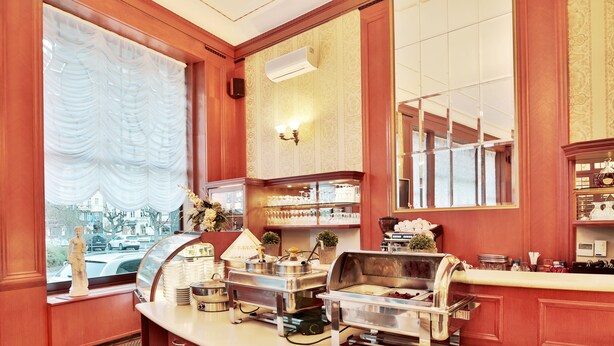 A buffet setup with various food stations, a statue, and a view of the street outside.