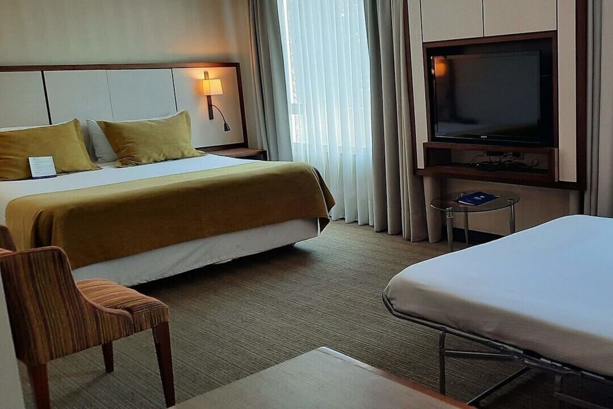 Een hotelkamer met twee bedden, een televisie, een kleine tafel en een stoel.