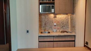 Una cocina compacta con encimera de granito, microondas y lavamanos.