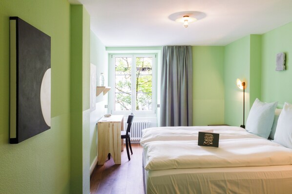 Un dormitorio con cama, escritorio y ventana con cortinas.