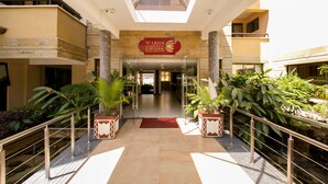 The entrance to the Waridi Paradise Hotel and Suites with a central glass door, surrounded by potted plants and a red carpet. - Waridi Paradise Hotel & Suites (Nairobi)