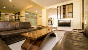 A modern living room with a leather sofa, a wooden coffee table, and a flat-screen TV mounted on the wall. - Waridi Paradise Hotel & Suites (Nairobi)