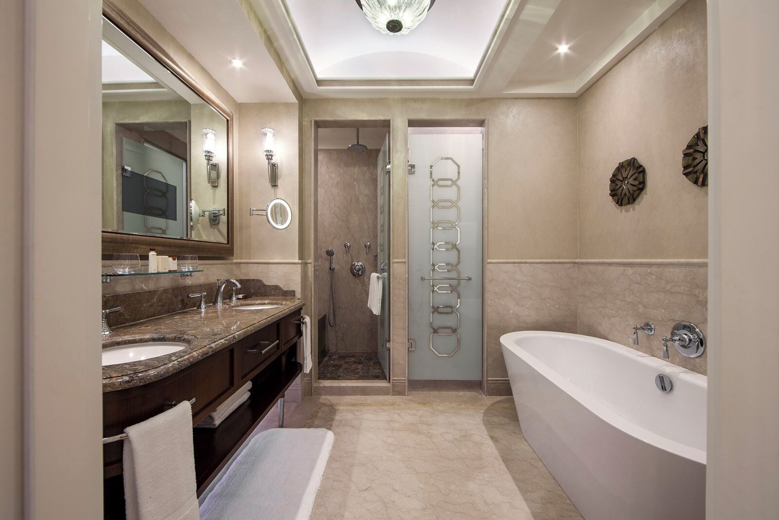 Une salle de bain moderne dotée d’une grande baignoire, d’un meuble-lavabo à deux vasques, d’une douche à l’italienne et d’un miroir agrémenté d’appliques murales.