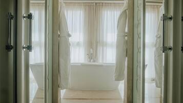 Une salle de bain avec une baignoire, un lavabo et une fenêtre avec des rideaux.