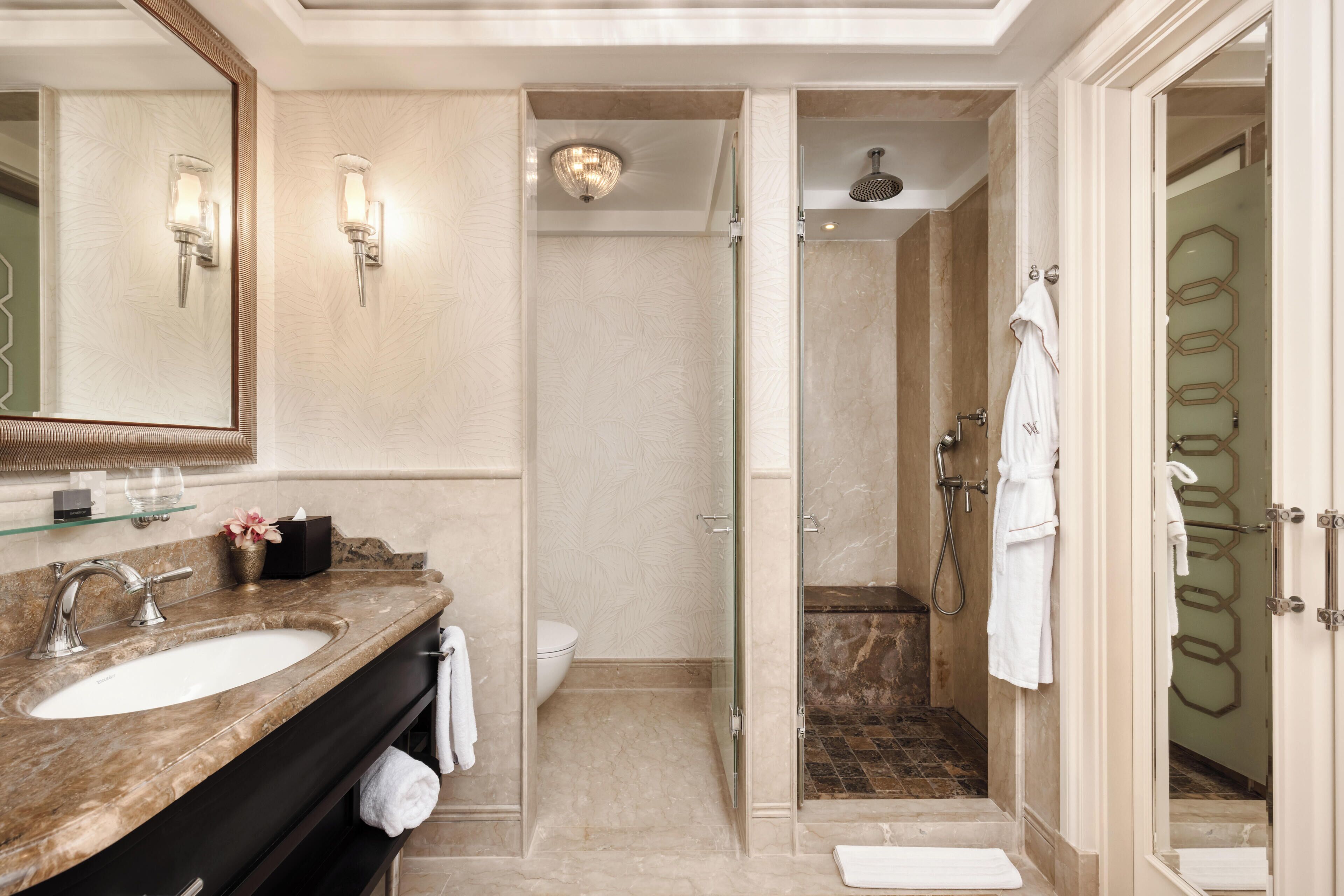 A bathroom with a marble sink, a glass shower enclosure, and a toilet.
