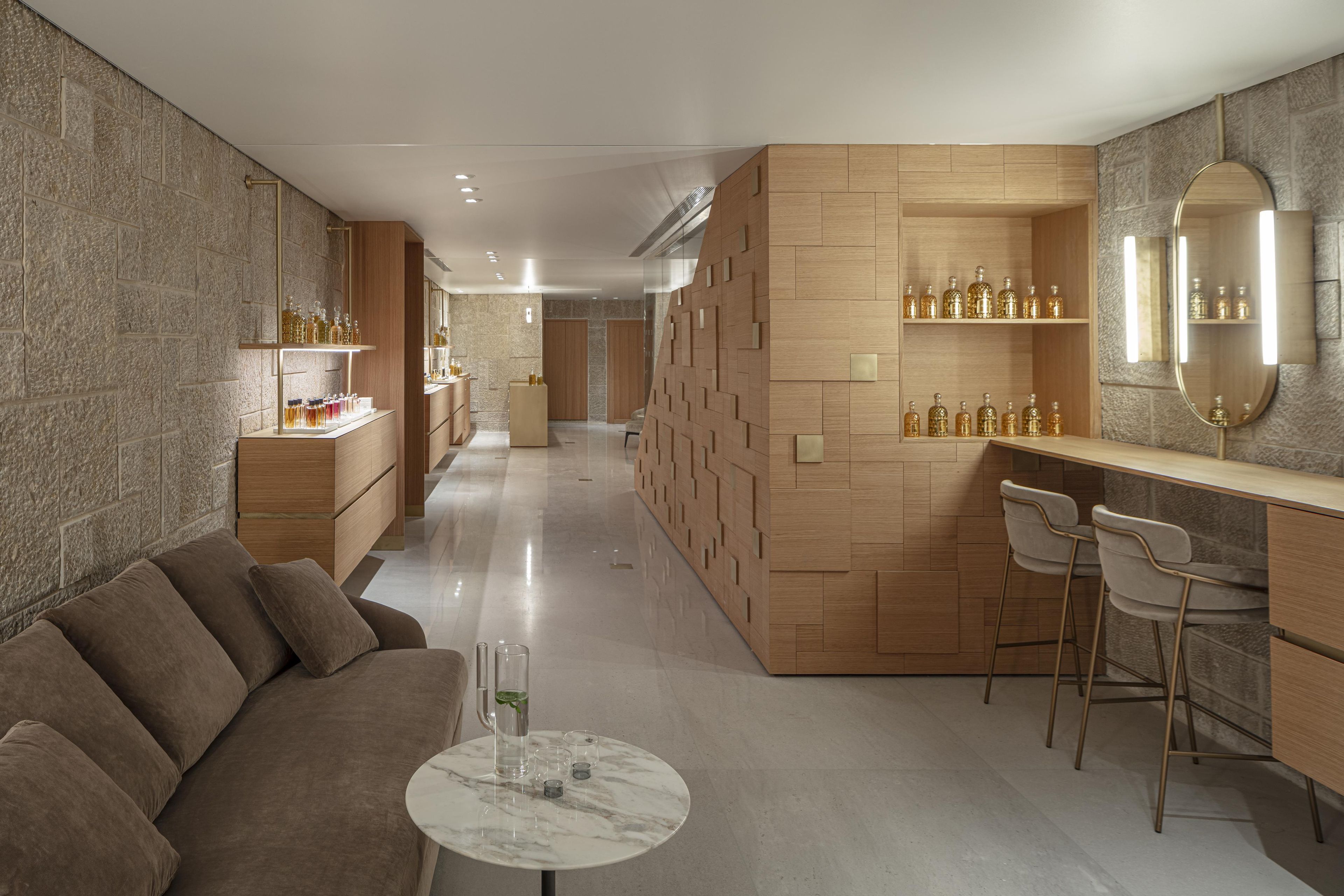 Un moderno vestíbulo de hotel con un sofá, una mesa de mármol y una zona de bar con taburetes.