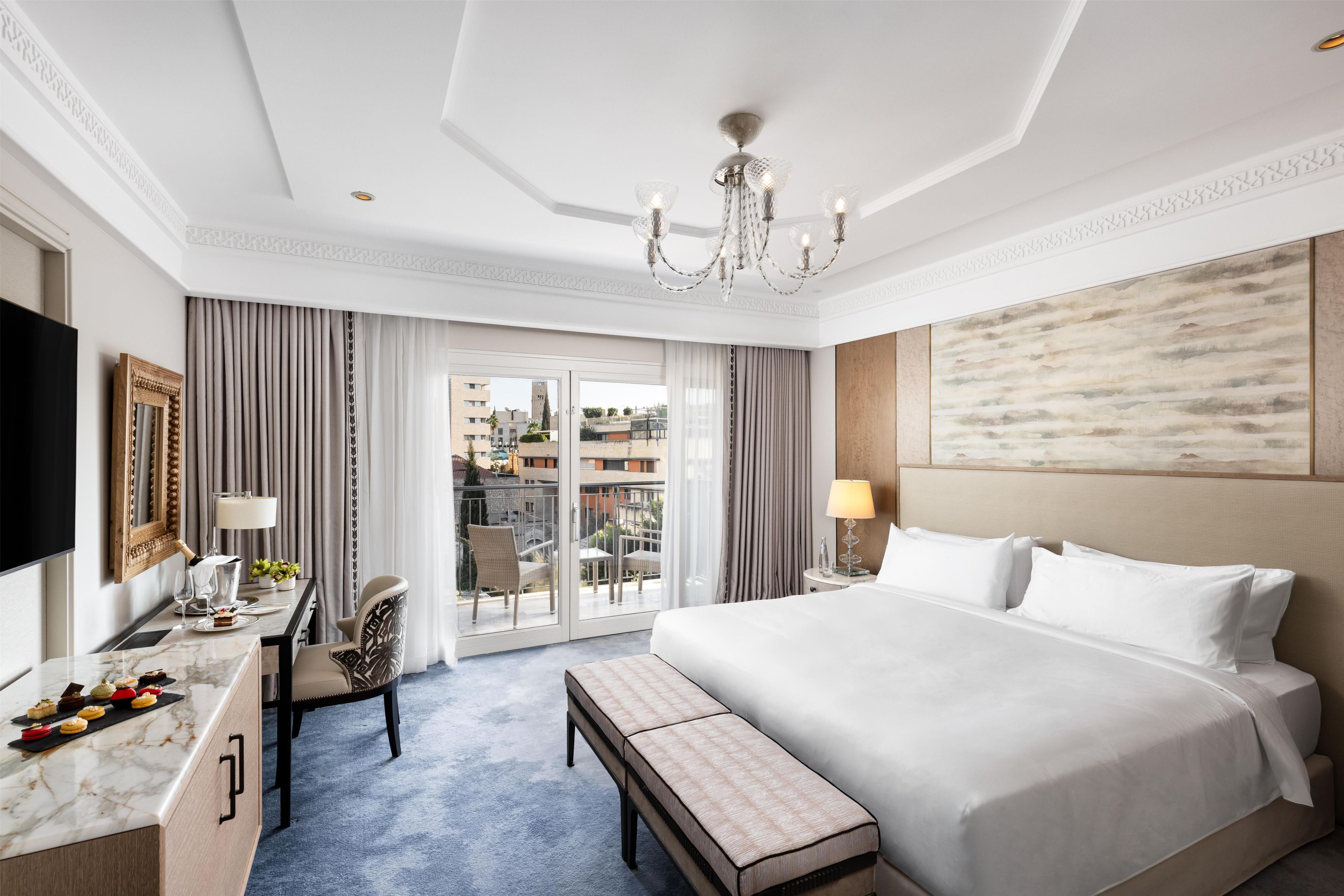 Une chambre d’hôtel avec un grand lit, un bureau avec une chaise, une télévision et une vue sur l’extérieur.