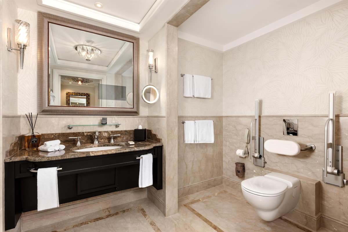 A modern bathroom with a large mirror, a sink, a toilet, and a shower area.