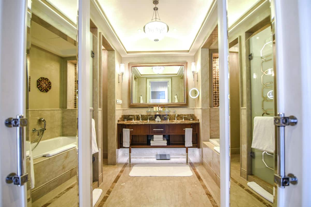 A modern bathroom with a large mirror, a bathtub, and a shower area.