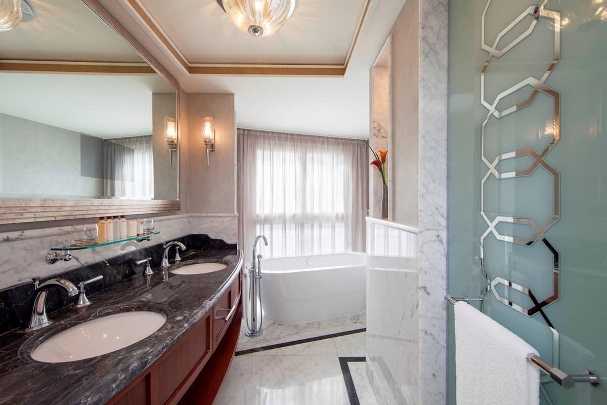 A bathroom with two sinks, a bathtub, and a large mirror.