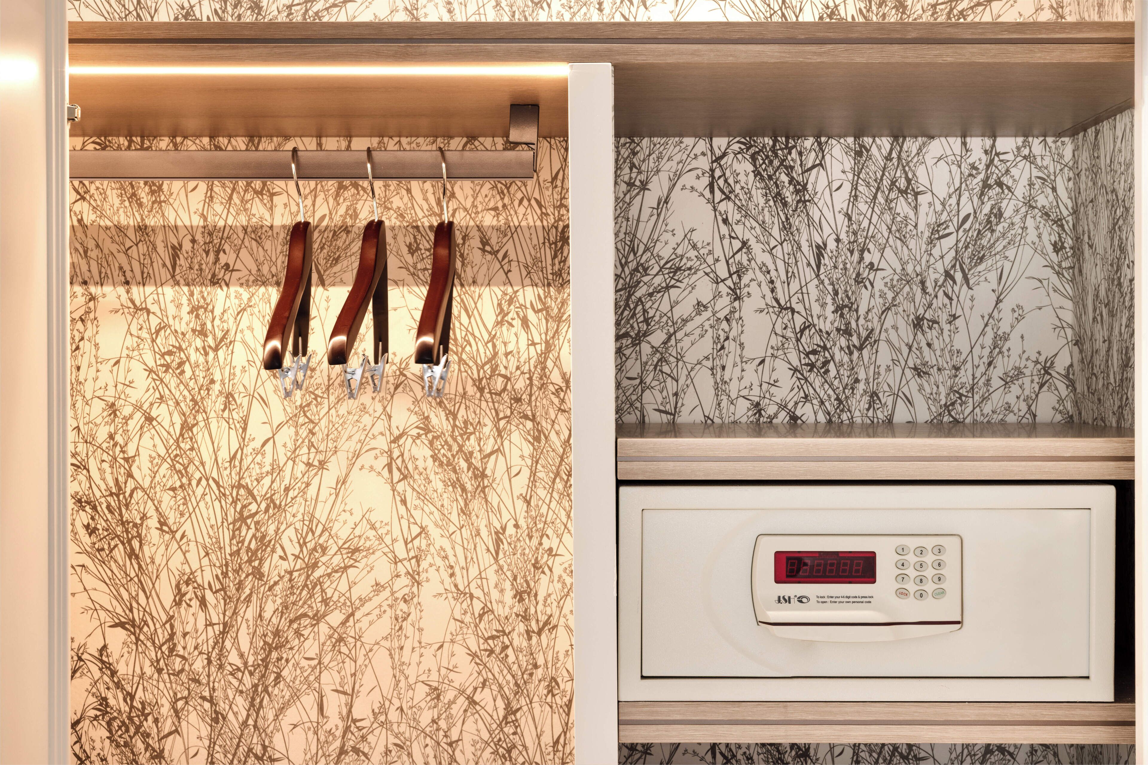 Uma cozinha com forno digital, um varal de utensílios e uma parede com padrão floral.