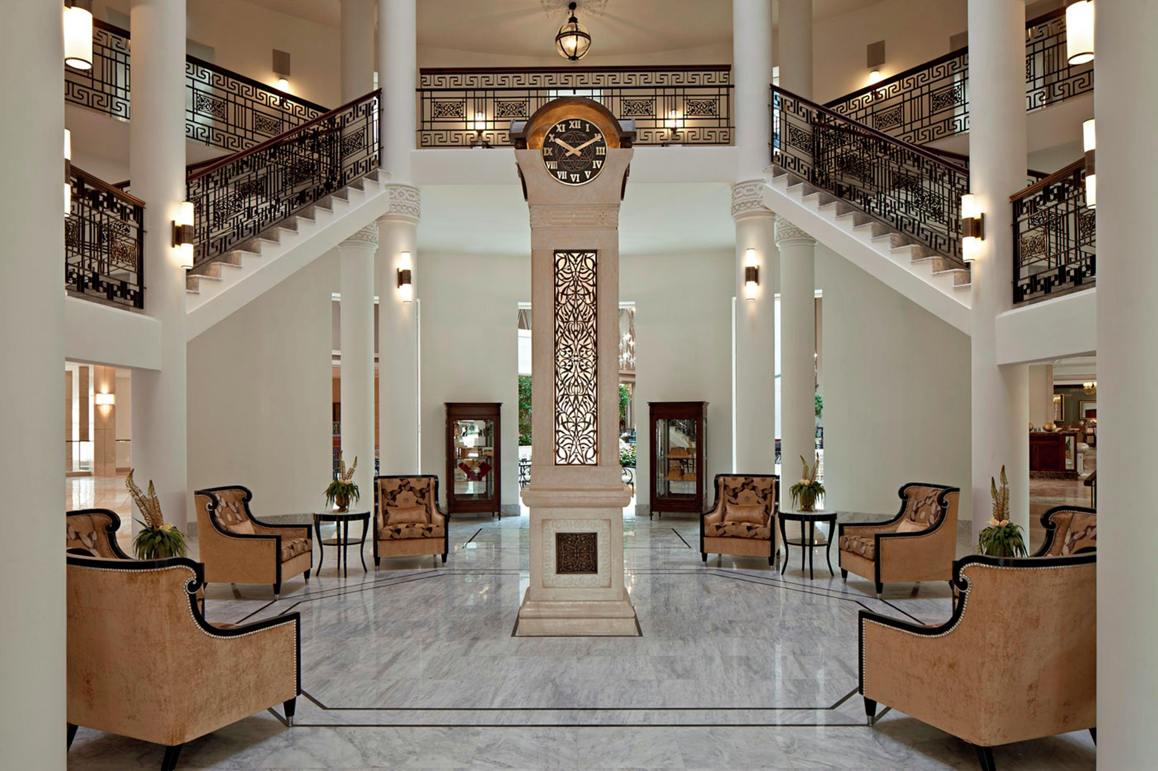 A grand lobby with a central column, a clock, and a staircase.