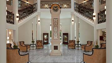 A grand lobby with a central column, a clock, and a staircase.