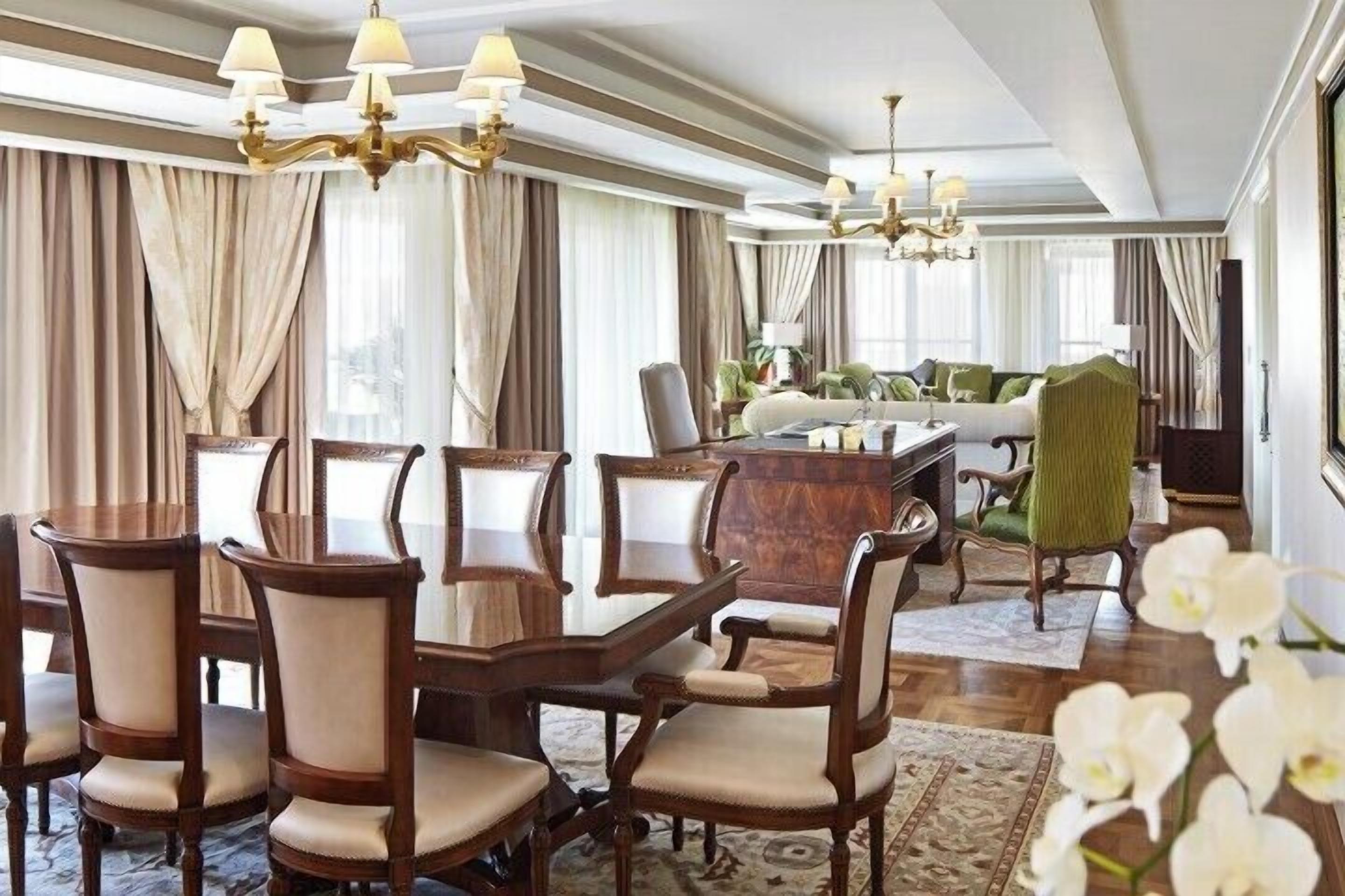 A formal dining room with a wooden table and chairs, a sofa, and a chandelier.