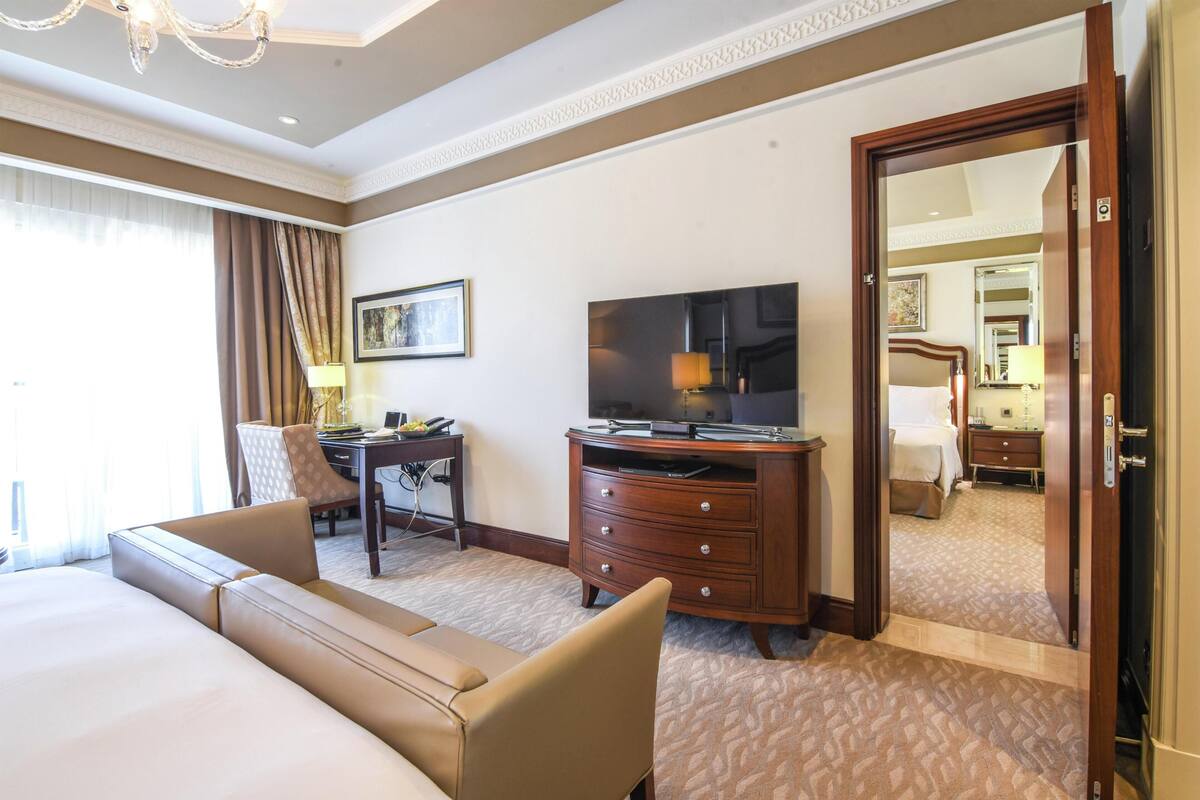 A hotel room with a bed, a desk, a television, and a mirror.