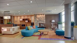 A modern lobby with a blue sofa, a wooden coffee table, and a reception desk. - Fairfield Inn & Suites Natchitoches (Natchitoches)