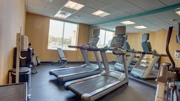 Une salle de sport équipée de tapis de course, d’appareils de musculation et d’un miroir.