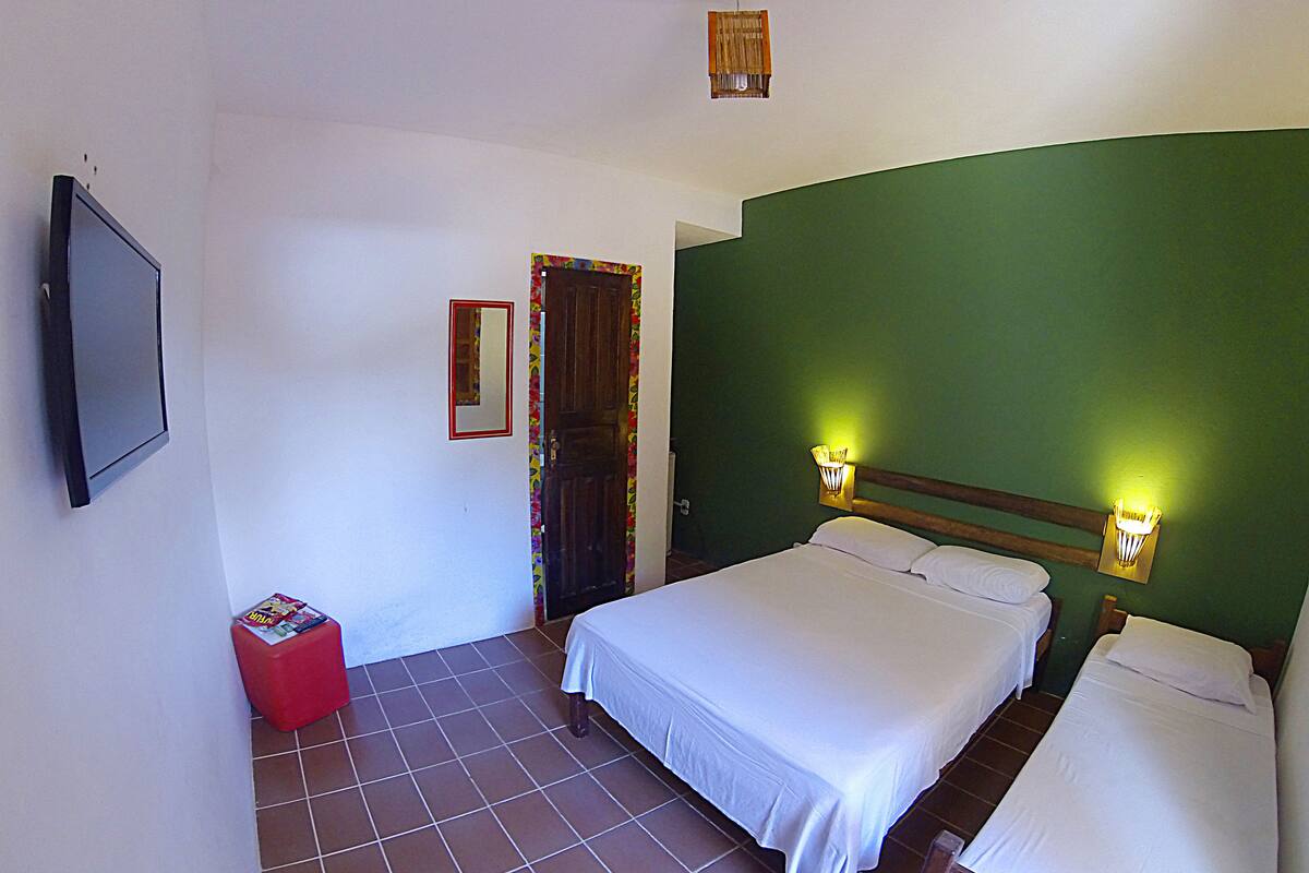 A hotel room with two beds, a television, and a red suitcase.