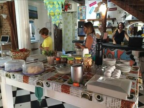 A buffet setup with various food containers, a coffee station, and a counter with a cash register.