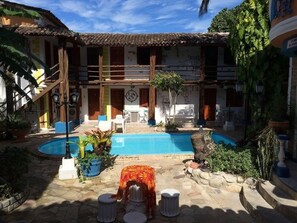 A courtyard with a swimming pool, outdoor seating, and a staircase leading to the upper level.