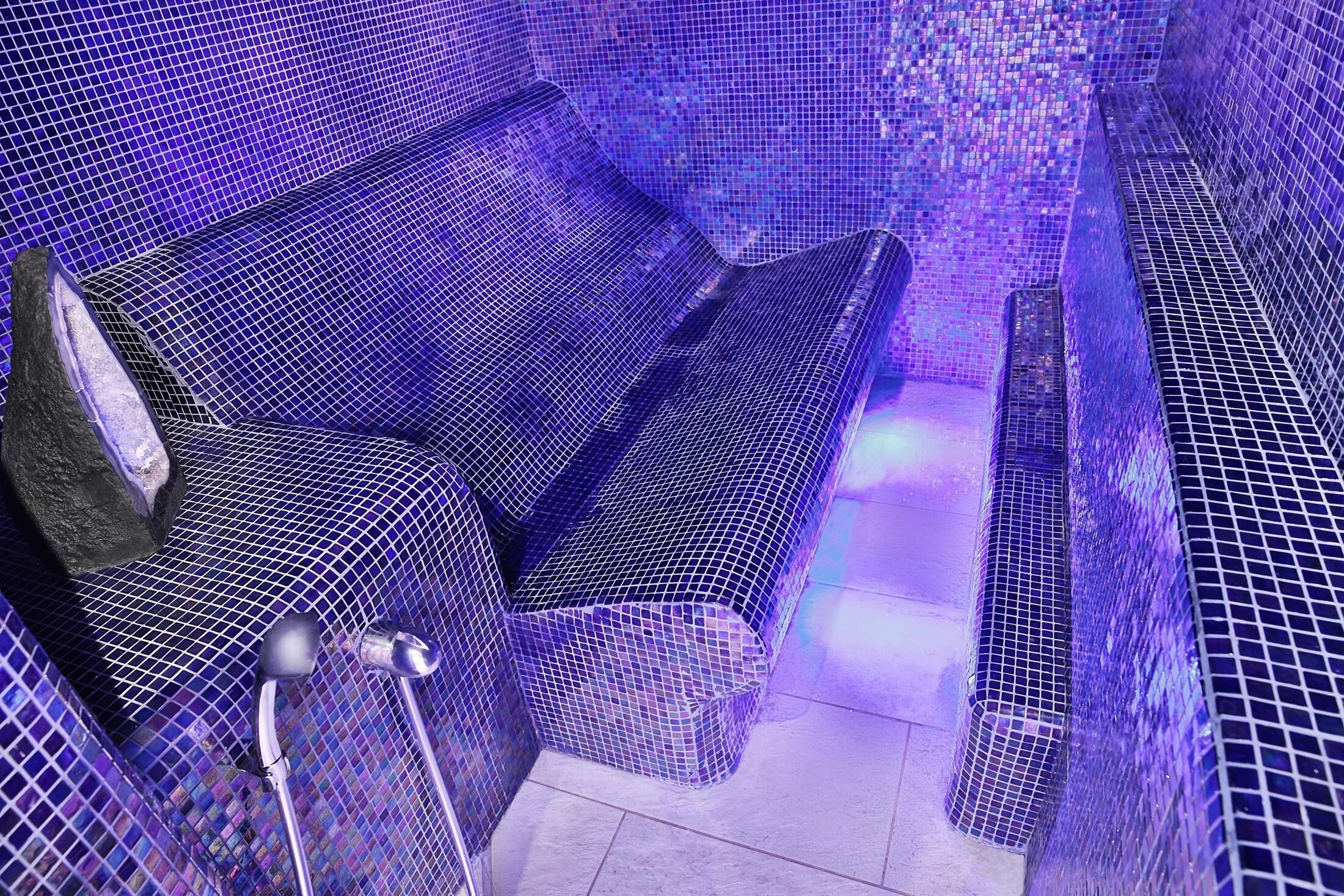 Una habitación con suelo de baldosas, un banco y una barandilla de metal.