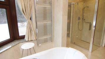 A bathroom with a glass-enclosed shower, a white bathtub, and a towel rack.