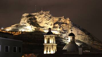 Vista nocturna de una montaña con una torre de campanas iluminada y una estructura en forma de cúpula.