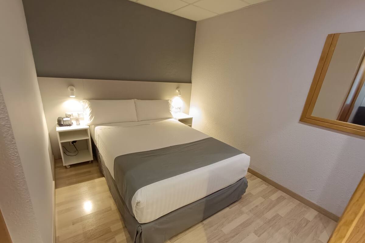 Une chambre à coucher bien rangée, avec un lit, des lampes de chevet et une table de chevet.