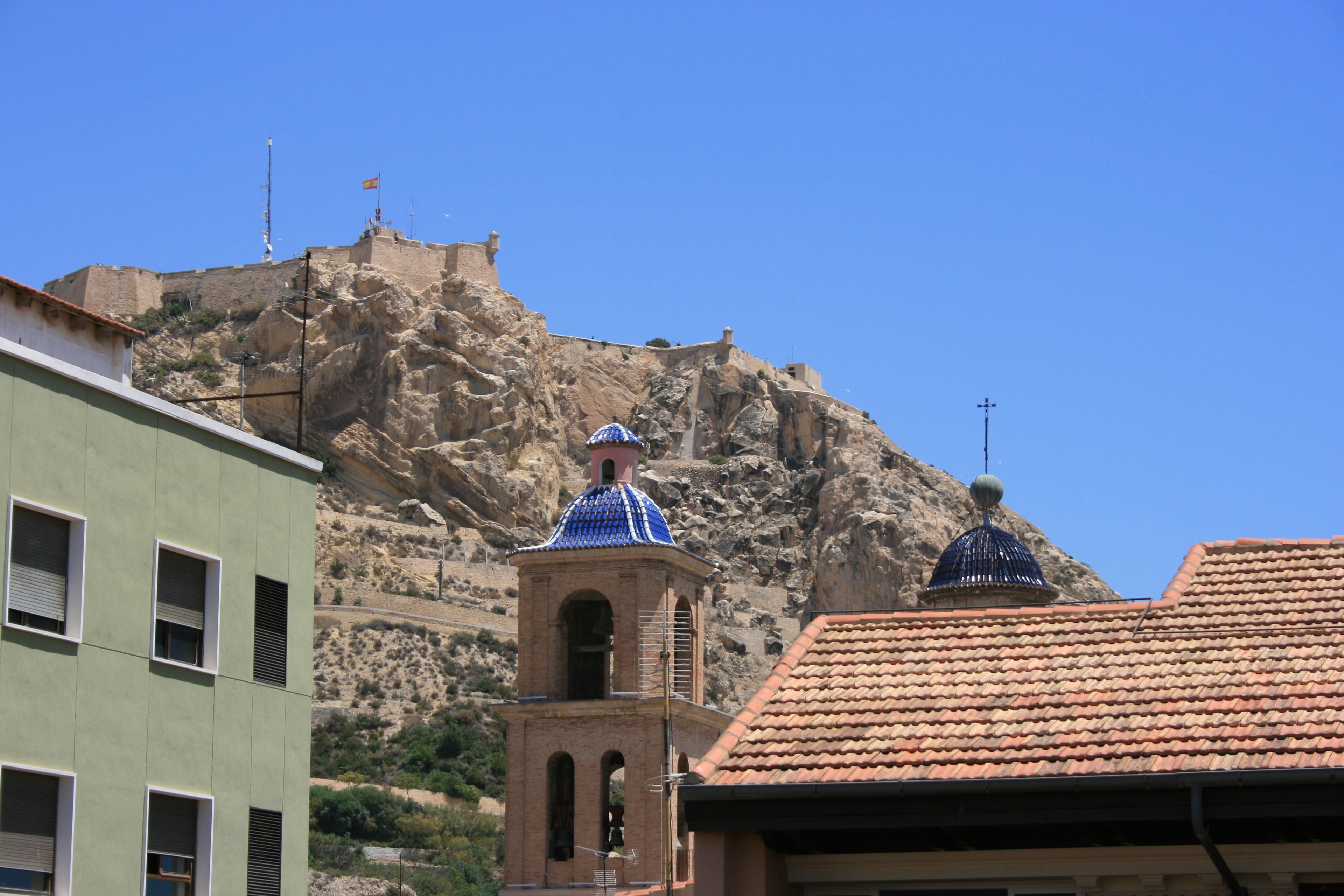 A building with a bell tower and a dome, set against a rocky hillside.
