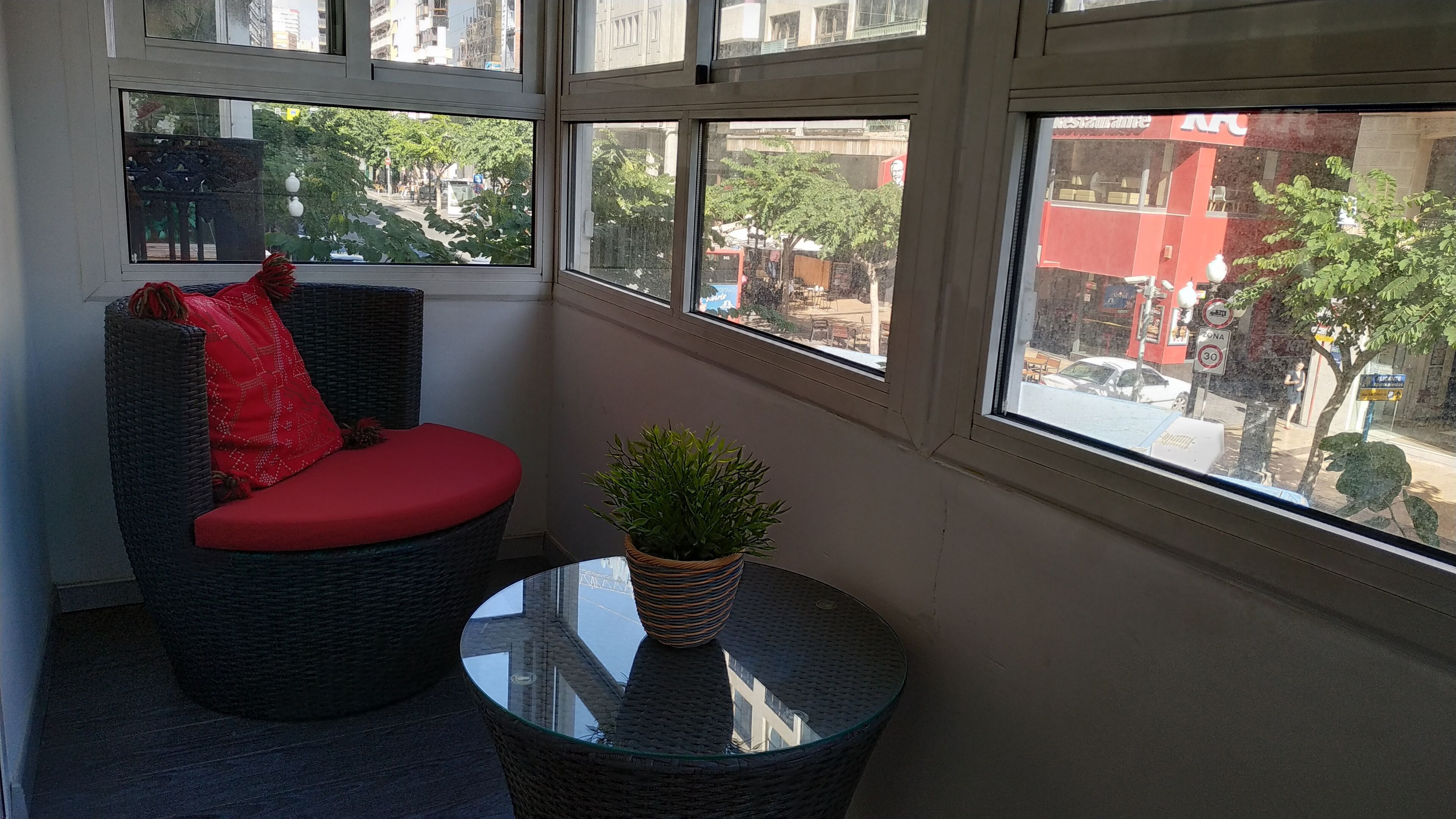 A corner room with a wicker chair and a small table with a potted plant.