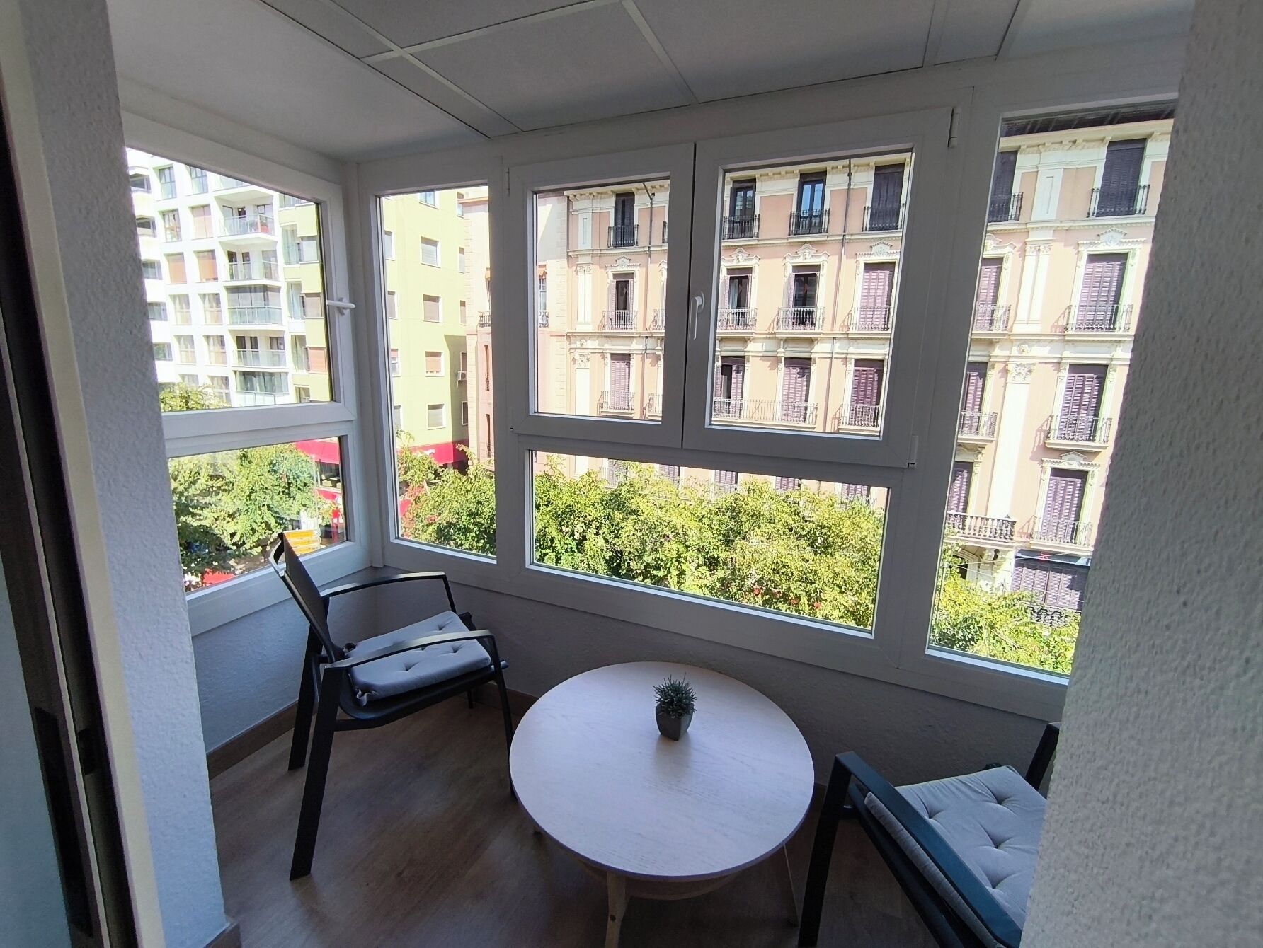 A balcony with a round table, two chairs, and a potted plant.
