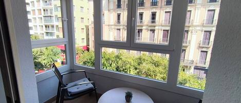 A balcony with a round table, two chairs, and a potted plant.