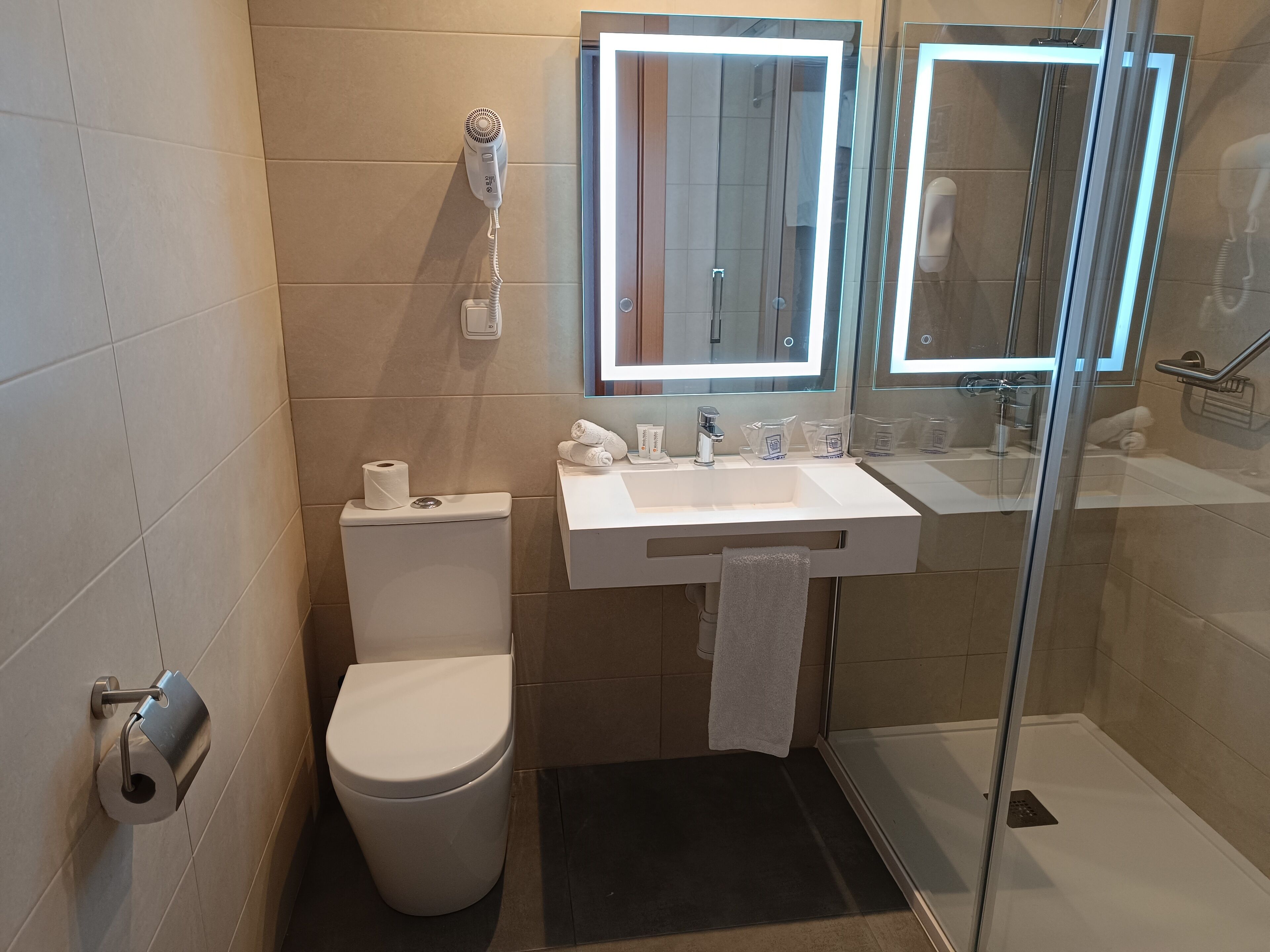 A modern bathroom with a toilet, sink, and glass shower enclosure.