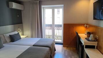 Une chambre d’hôtel avec deux lits, un bureau, une chaise, une télévision et un balcon avec vue.