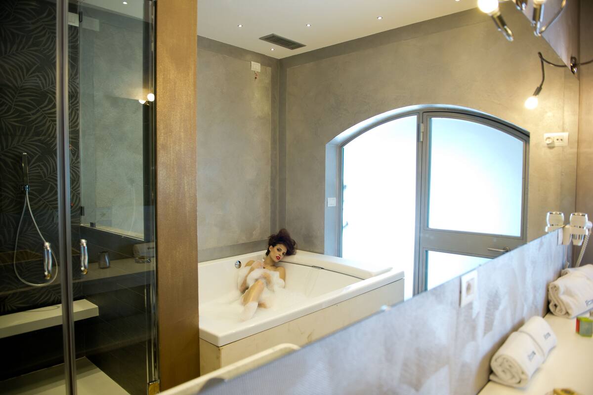 Un baño moderno con ducha de vidrio, bañera y tocador con toallas.