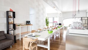 A modern kitchen with a long white countertop, wooden chairs, and a built-in bookshelf. - WRooms Colosseum (Rome)