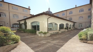 A courtyard with a building featuring arched windows and a tiled roof. - WRooms Colosseum (Rome)