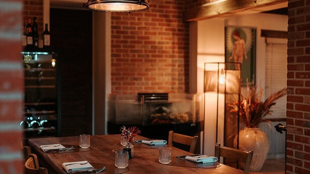 A dining area with a wooden table, chairs, and hanging pendant lights. - Hotel Ter Zuidhoek (Roeselare)