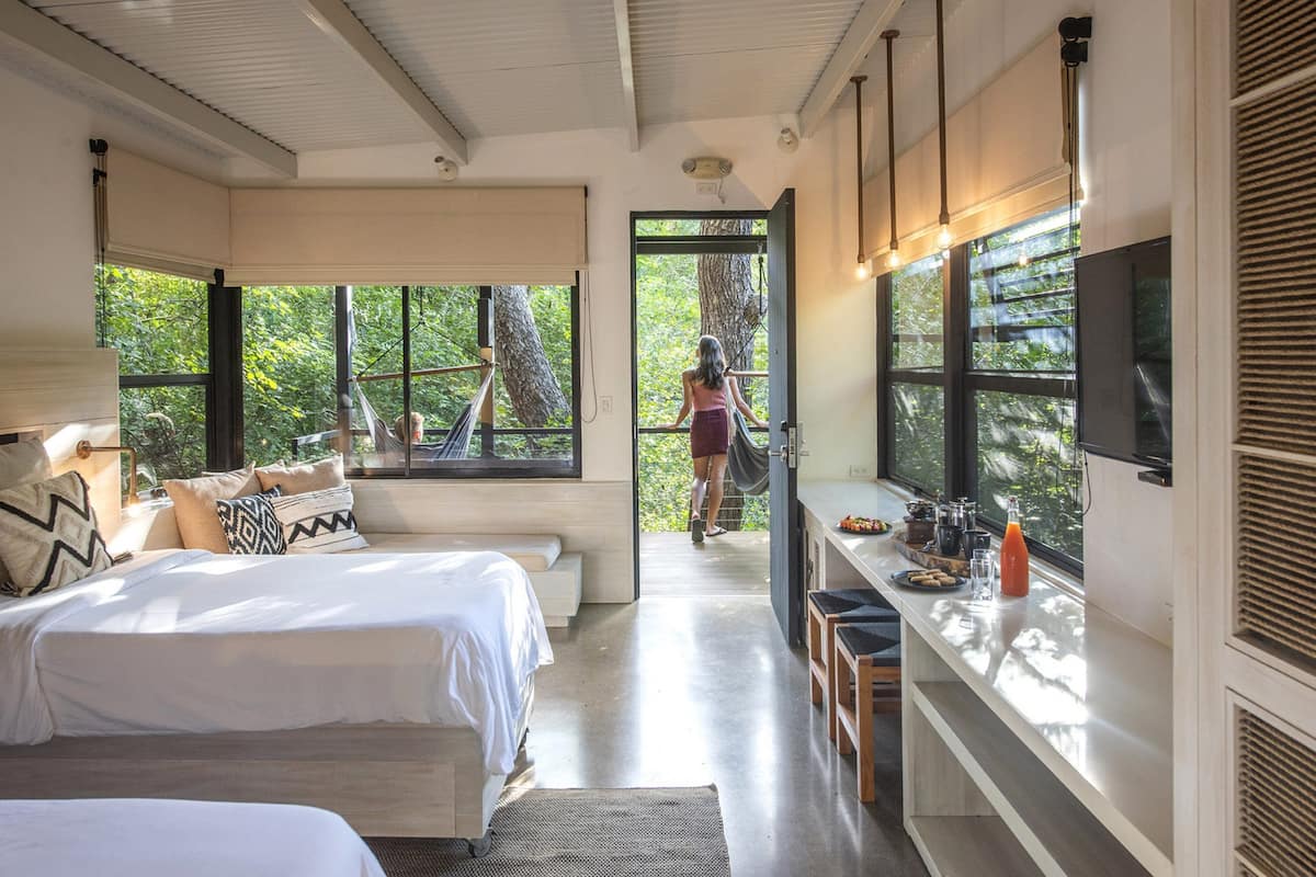 A modern hotel room with a large bed, a sitting area with a view, and a breakfast bar.