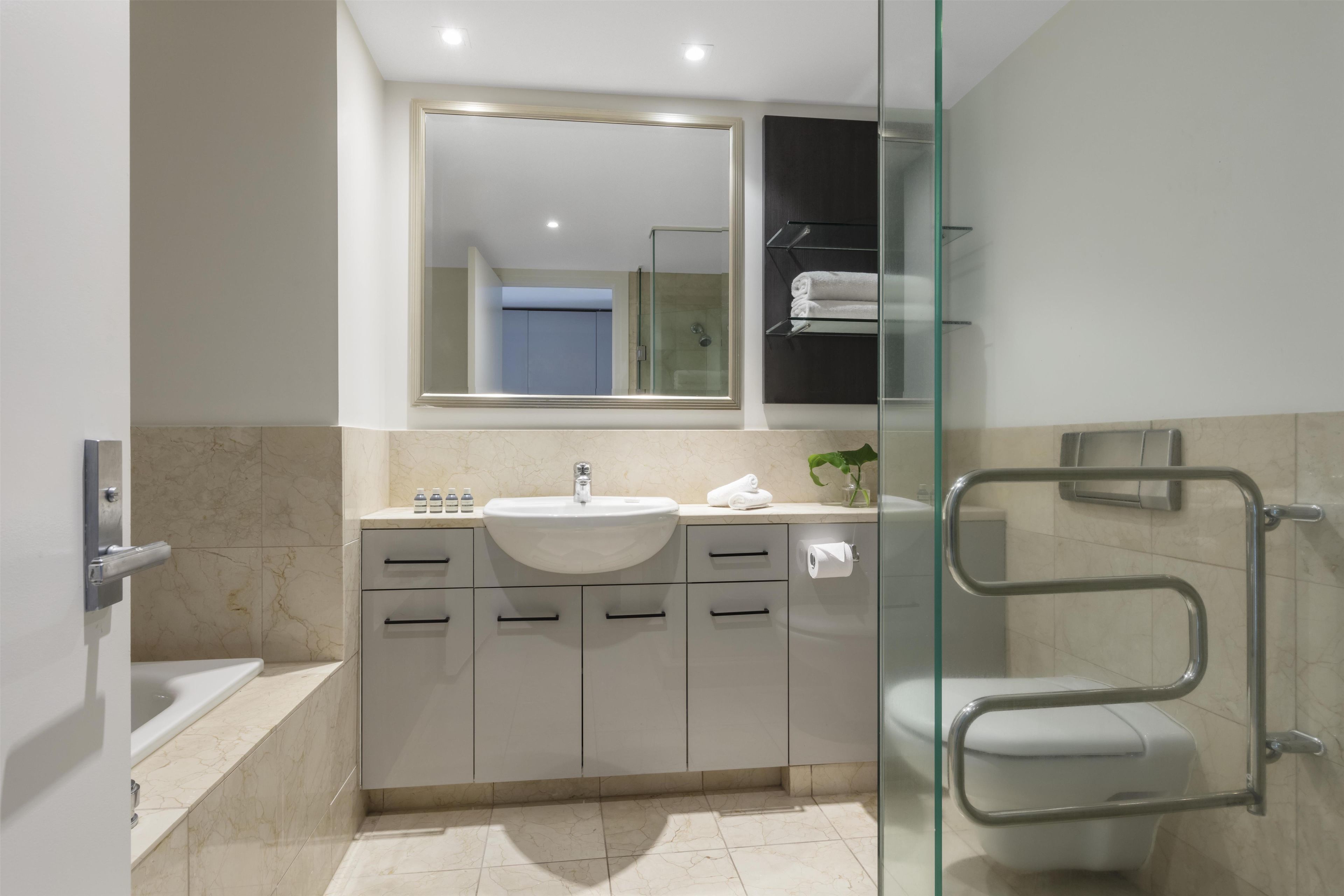 Une salle de bain moderne avec une douche à parois de verre, un lavabo blanc et un meuble-lavabo avec des tiroirs.
