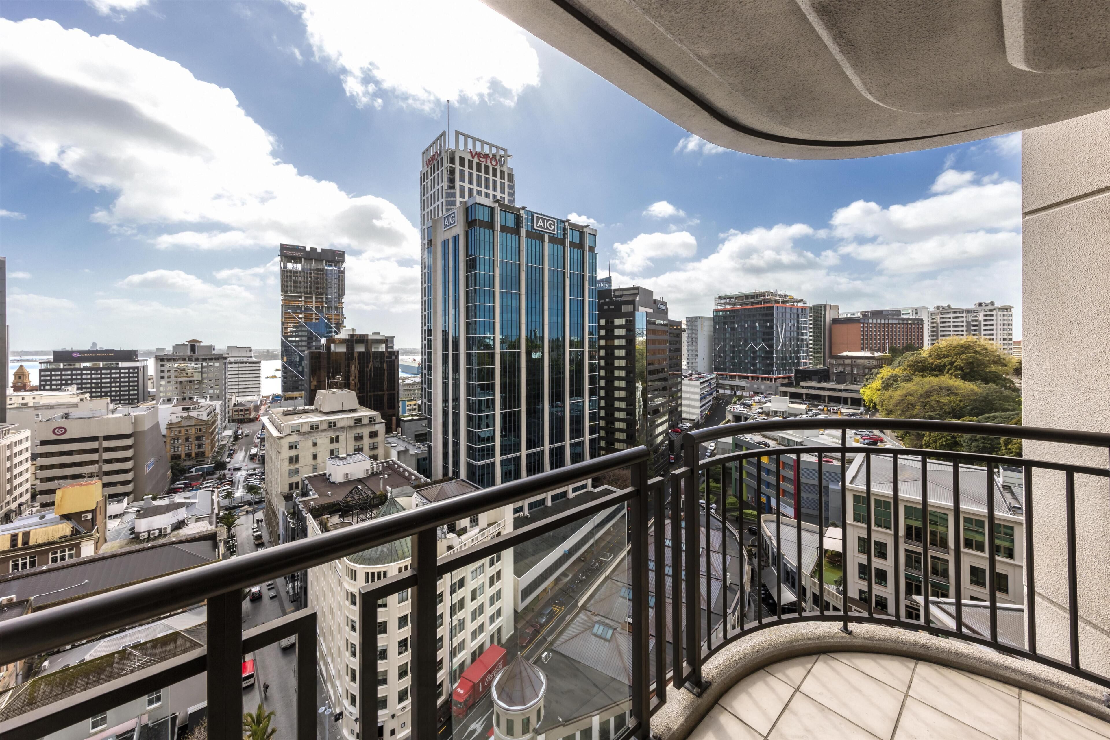 A high-rise building with a modern glass facade, a view of the cityscape, and a balcony railing.