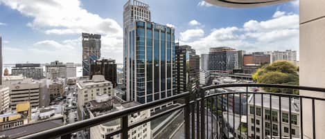 A high-rise building with a modern glass facade, a view of the cityscape, and a balcony railing.