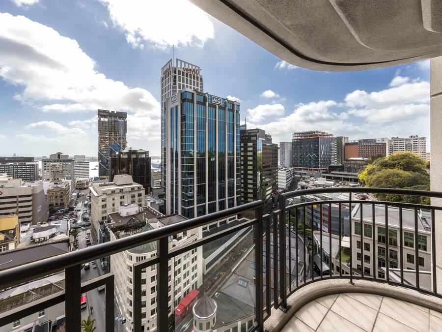 Um edifício alto com fachada de vidro moderna, vista para a cidade e guarda-corpo de varanda.
