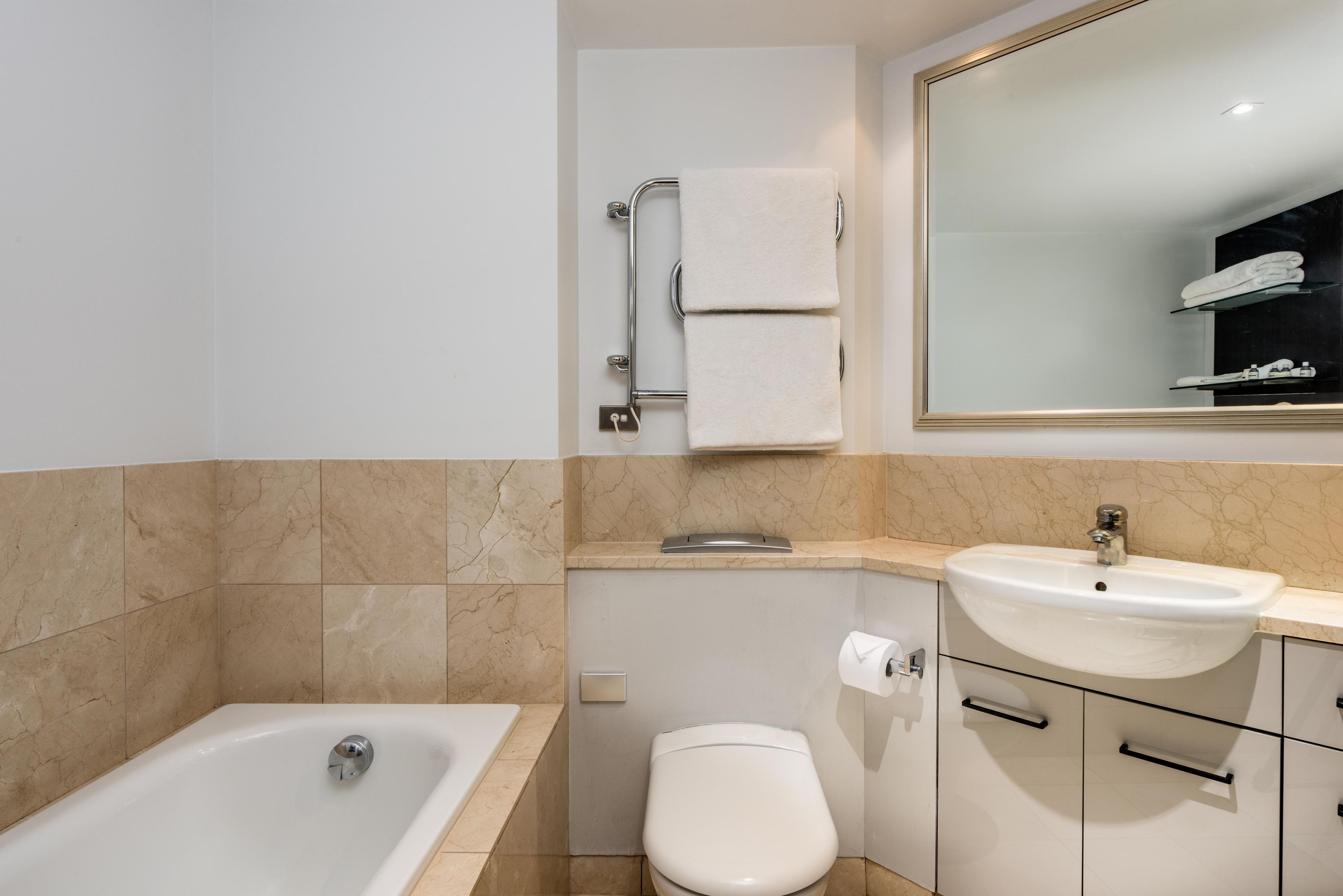 A bathroom with a bathtub, toilet, sink, and a mirror.