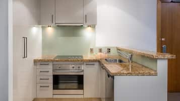 Una cucina compatta con forno integrato, lavello e piano di lavoro.
