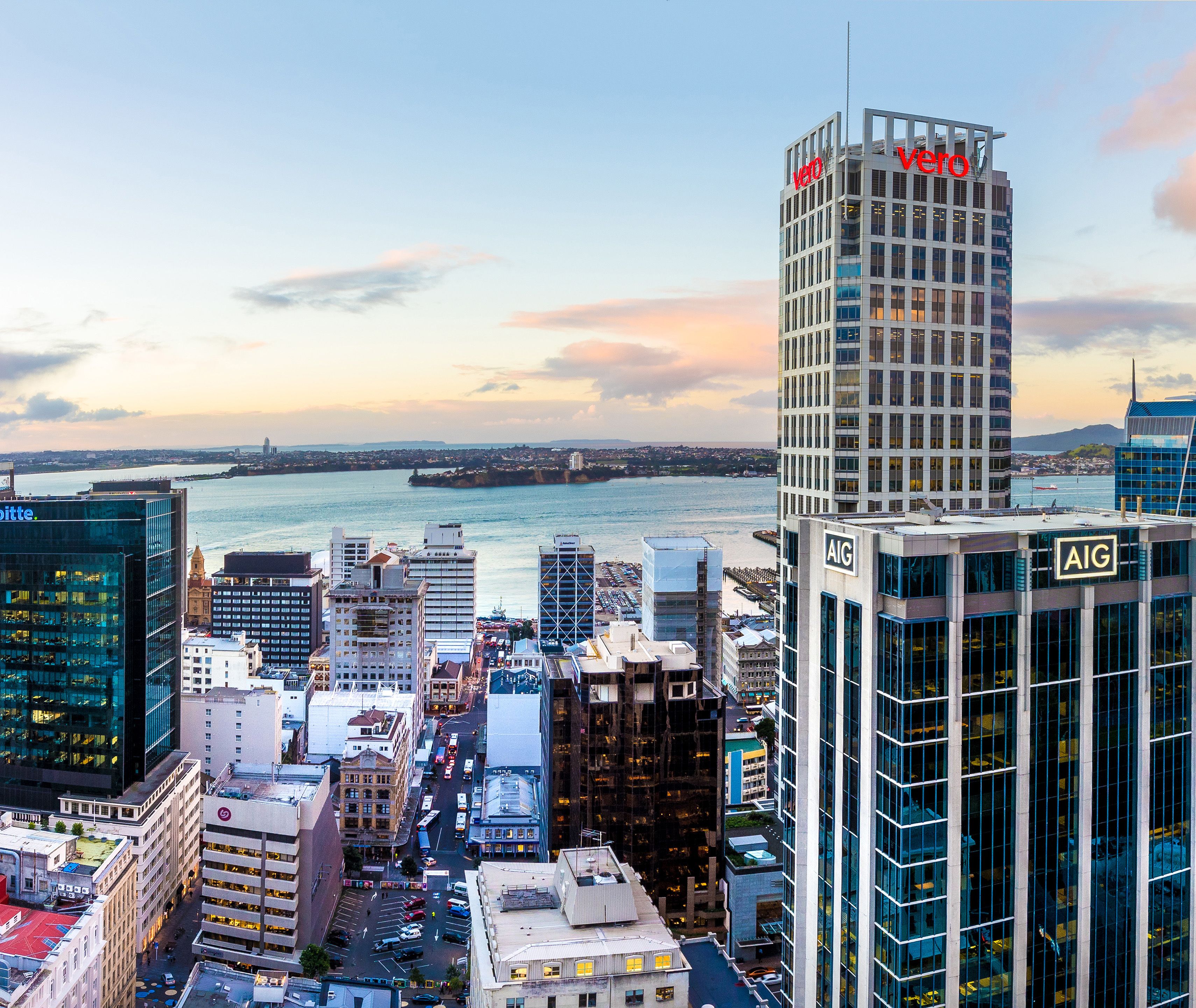 A high-rise building with "vero" signage, surrounded by other buildings and a waterfront.