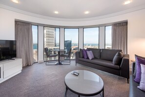 A modern hotel room with a large window, a sofa, a coffee table, and a TV. - Avani Auckland Metropolis Residences (Auckland)