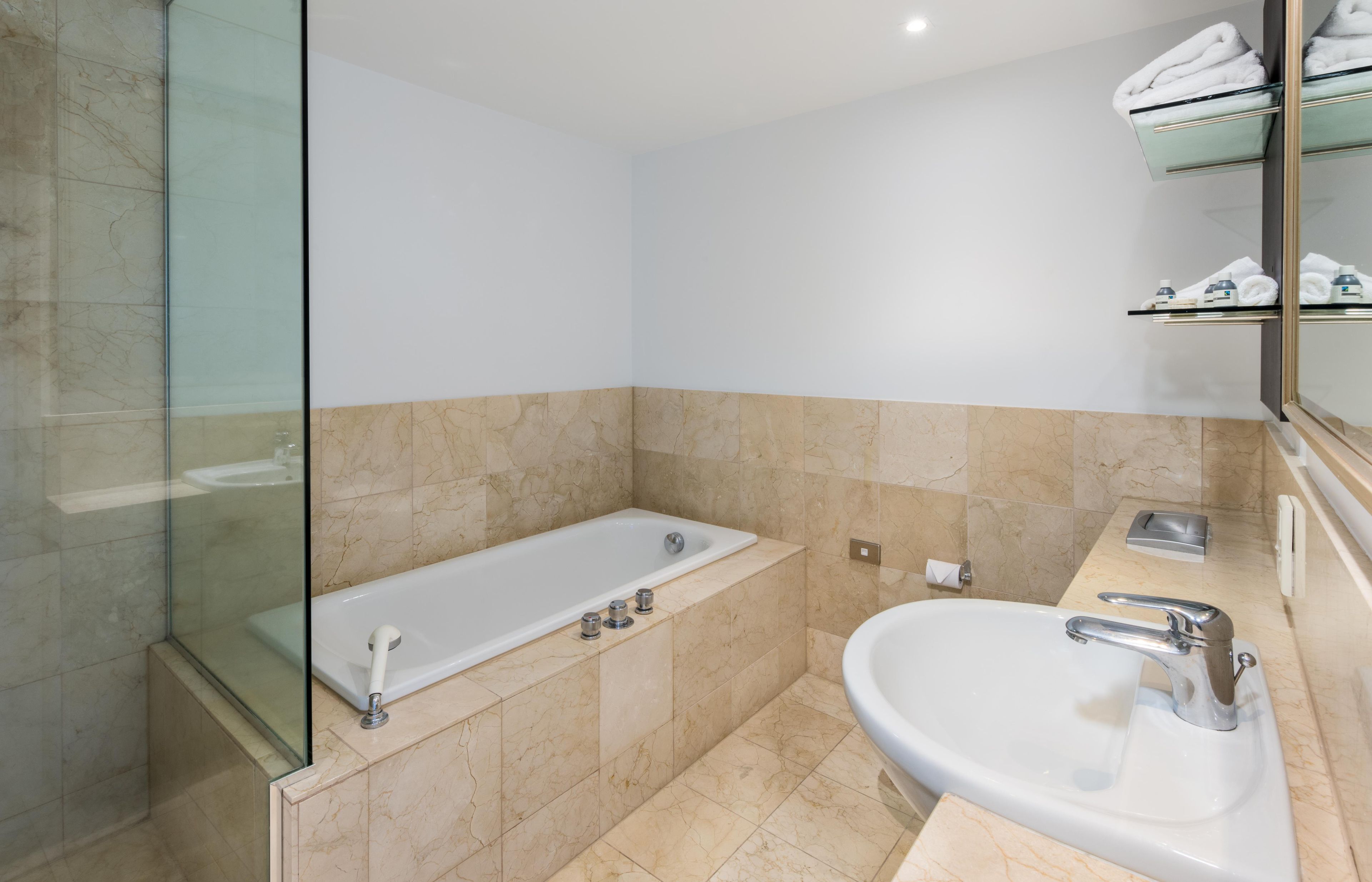 A modern bathroom with a glass shower enclosure, a bathtub, and a sink with a mirror.